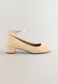 Beige Blockabsatzschuh mit Obermaterial aus strukturiertem Stoff, runder Zehenpartie und Knöchelriemen mit Schnalle. Flache Sohle für zusätzliche Stabilität.