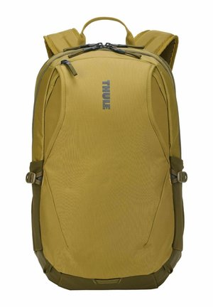 Sac à dos compact vert olive avec bretelles rembourrées, sangles de compression latérales, poignée supérieure et poche avant zippée avec logo Thule.