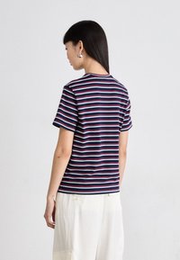 T-shirt rayé marine avec des bandes horizontales blanches et rouges, à manches courtes et col rond. Tissu doux avec une coupe décontractée.