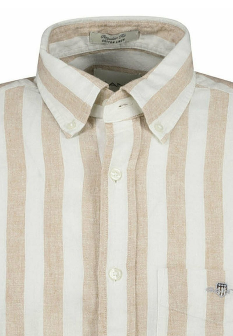 Camicia con bottoni in una miscela di lino e cotone. Presenta righe verticali crema e beige, un colletto classico e una tasca a toppa sul petto.