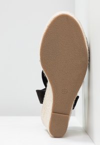 Sandale compensée avec une tige en tissu noir texturé, talon recouvert de corde naturelle et semelle en caoutchouc. Taille indiquée comme 37 sur la semelle.