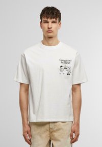Witte katoenen t-shirt met korte mouwen en een grafische print van karakters en de tekst "Contemporary Art Market" op de voorkant.