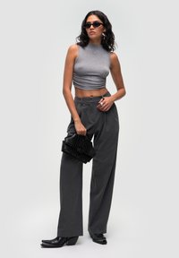 Grå, cropped, ærmeløs top, højtaljede mørkegrå bukser, sort struktureret håndtaske og sorte firkantede hæle. Glat tekstur; skræddersyet design.