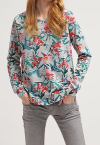 Sudadera floral en gris claro, con vibrantes flores rojas y rosas acompañado de hojas verdes. Manga larga, cuello redondo y corte relajado.