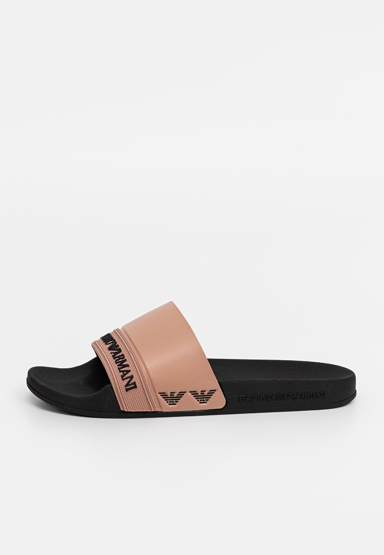 Chancleta de goma rosa con una tira texturizada y suela negra. Presenta un logo grabado y detalles de marca en el lateral.