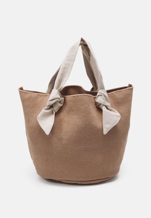 Sac fourre-tout tissé brun à la surface texturée, avec deux anses en tissu clair nouées en nœud sur le dessus.