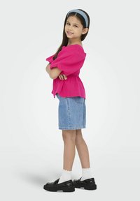 Lyserød top med puffærmer og samlet talje, denim shorts, hvide blonderstrømper, sorte lak-sko og et lyseblåt pandebånd.