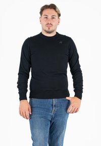 Maglione nero a maniche lunghe con scollatura rotonda e orlo a costine, realizzato in un tessuto a maglia liscia, con un piccolo logo sul petto.