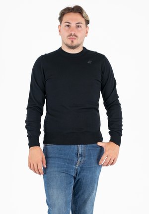 Maglione nero a maniche lunghe con scollatura rotonda e orlo a costine, realizzato in un tessuto a maglia liscia, con un piccolo logo sul petto.