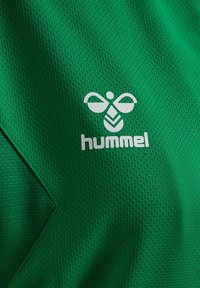Groene sporttrui van een gemêleerde stof met een ruitpatroon en een wit logo van "hummel" aan de voorkant.