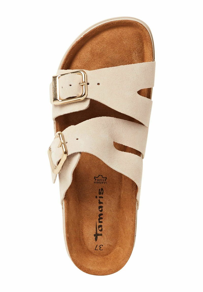 Beige suède sandaal met twee uitgesneden banden, verstelbare gouden gespsluiting en een gevoerde bruine binnenzool met logo van het merk. Platte zool.