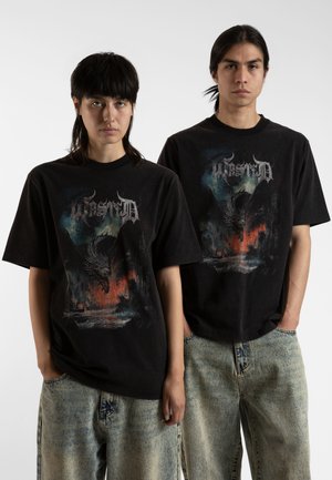 T-shirts en coton noir avec un imprimé graphique coloré de dragon avec des accents rouges et bleus. Coupe ample, manches courtes et design col rond.