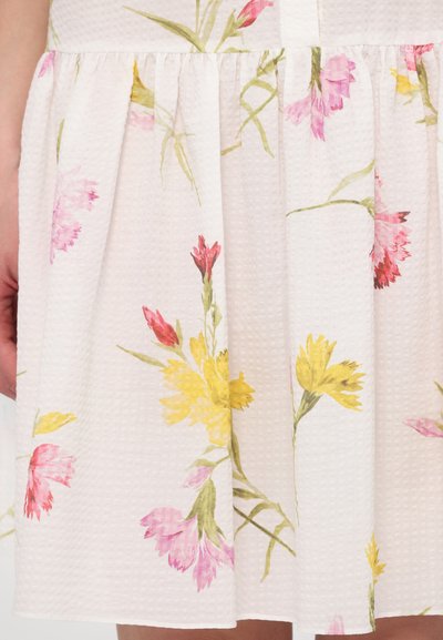 White floral dress with pink, yellow, and green flowers. Textured fabric with pleats, showcasing a light and airy design.
