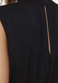 Mörkblå klänning med hög halsringning, korta ärmar och ett nyckelhål bak, tillverkad av mjukt och lätt material.