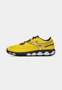Baskets de sport jaunes avec des accents noirs, tige texturée et semelle en forme de vague rembourrée. Présente des lacets noirs et un logo de la marque.