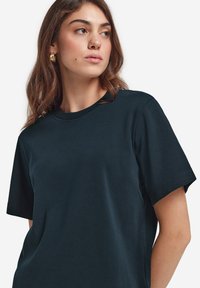 Mörk marinblå bomullströja med rund hals och korta ärmar, med avslappnad passform och subtil textur. Minimalistisk design utan mönster.