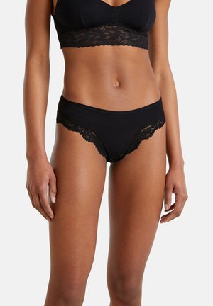 Zwarte panty's met kantafwerking, gemaakt van een gladde stof, met een lage taille en delicate kantaccenten langs de tailleband en de beenopeningen.
