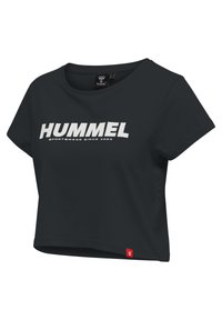 Černý crop top vyrobený z měkké tkaniny, s výrazným bílým logem "HUMMEL" a textem "SPORTWEAR SINCE 1923", s červenou akcentovou štítkem na lemu.