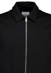 Zwarte bomberjack met ritssluiting en kraag. Gemaakt van textuurbare stof, voorzien van zijzakken en een minimalistisch ontwerp. Zilveren ritsaccent.