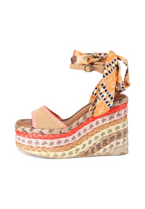 Sleehaksandaal met meerkleurig gevlochten plateau, roze suède voorband en oranje enkelband met patroon en gespsluiting.