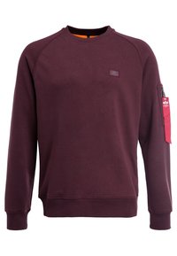 Bordeauxrotes Sweatshirt mit Rundhalsausschnitt, Raglanärmeln, strukturierter Stoff und orangefarbenem Innenfutter. Verfügt über einen seitlichen Reißverschluss und ein Markenpatch.