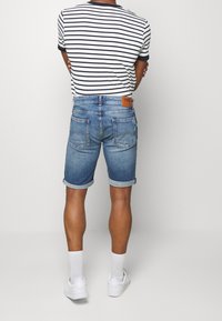 Ljusblå denimshorts med uppvikta fållar; parat med en randig svart och vit t-shirt, bärs med vita sneakers och knästrumpor.