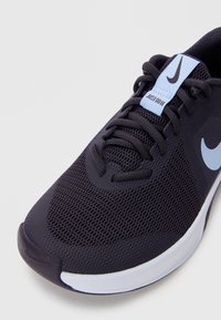 Fekete hálós sportcipő sima gumi talppal, világoskék részletekkel és kiemelkedő fekete Swoosh logóval. Textúrázott dizájn az egész felületen.