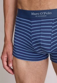 Bóxers a rayas azul marino con líneas horizontales azul claro. Presenta una cinturilla suave con la marca "Marc O'Polo". Material de algodón.