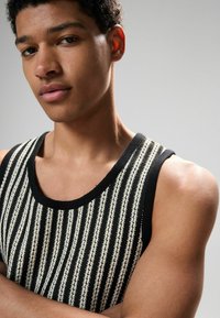 Schwarz-weiße gestreifte Tanktop mit rundem Ausschnitt und strukturiertem Strick. Der Stoff zeichnet sich durch abwechselnd solide und gemusterte Streifen aus.