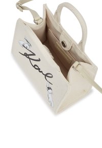 Borsa in tela di colore crema, dotata di una tasca interna. Sul davanti riporta la scritta in corsivo nera "Karl" e personaggi illustrati. Inclusa una tracolla regolabile.