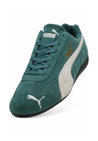 Baskets en daim turquoise Puma avec une bande latérale blanche, logo Puma blanc à l'embout, marquage Puma doré sur le côté et lacets turquoise.