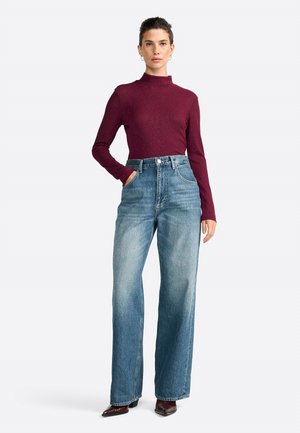 Haut à col roulé ajusté bourgogne à manches longues, associé à un jean évasé bleu clair taille haute et des bottes à bout pointu.