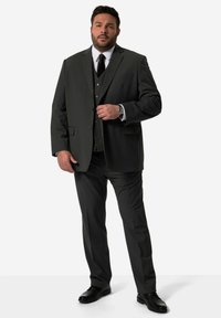 Mörkgrå kostym med tre-delsdesign, strukturerad tyg, enfärgad kavaj och svart slips. Svarta skor fulländar outfiten.