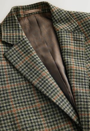 Wool blazer featuring a green, black, and orange houndstooth pattern, with a smooth brown satin interior and notch lapels.