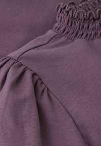 Paarse katoenen kleding met geplooide smocking bij de halslijn en geplooid detail langs de schoudernaad. Zachte, gladde textuur.