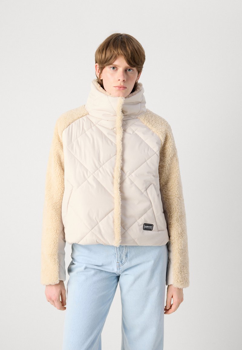 Giacca a vento con corpo beige trapuntato e maniche fluffy color sabbia. Collo alto con cerniera frontale. Piccolo logo nero in basso a sinistra.