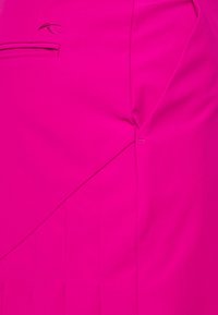 Tela fucsia con una textura suave, que presenta un detalle de costura diagonal y una puntada de acento cerca de una sección doblada.