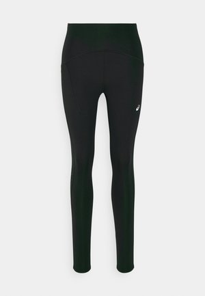 Black leggings with a high waist design, featuring a smooth texture and side pockets. Subtle reflective accents and a logo detail present.