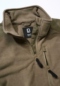 Fleece jacket in olive green with a half-zip collar, contrasting shoulder panels, and zippered pockets with black pulls. Soft texture.