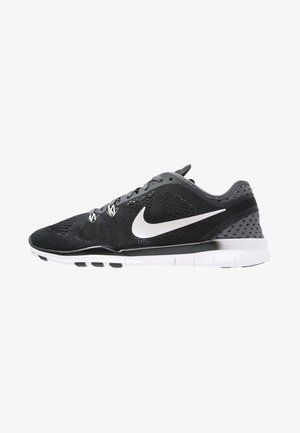 Zapatilla de running Nike negra y gris con logo swoosh blanco, parte superior transpirable de malla y suela segmentada blanca, vista de lado.