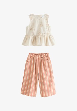 Haut sans manches crème avec broderie florale et ourlet volanté, associé à un pantalon large à rayures verticales roses et blanches avec taille élastique et poches.
