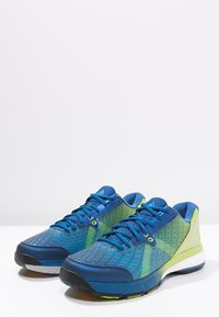 Niebieskie buty sportowe z teksturowaną siateczką, odblaskowymi akcentami i poduszkowaną podeszwą, z żółtymi detalami i minimalistycznym designem.