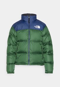 Veste matelassée verte et navy avec fermeture éclair complète, col montant, deux poches latérales et le logo The North Face sur la poitrine.