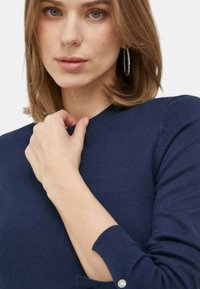 Maglione blu navy con scollatura rotonda, polsini a coste e dettaglio con bottone sulla manica, realizzato in un morbido materiale a maglia.