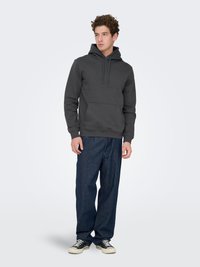 Gray hoodie with a front pocket and drawstring hood, paired with loose-fitting dark blue jeans and black sneakers. Simple design, no patterns.