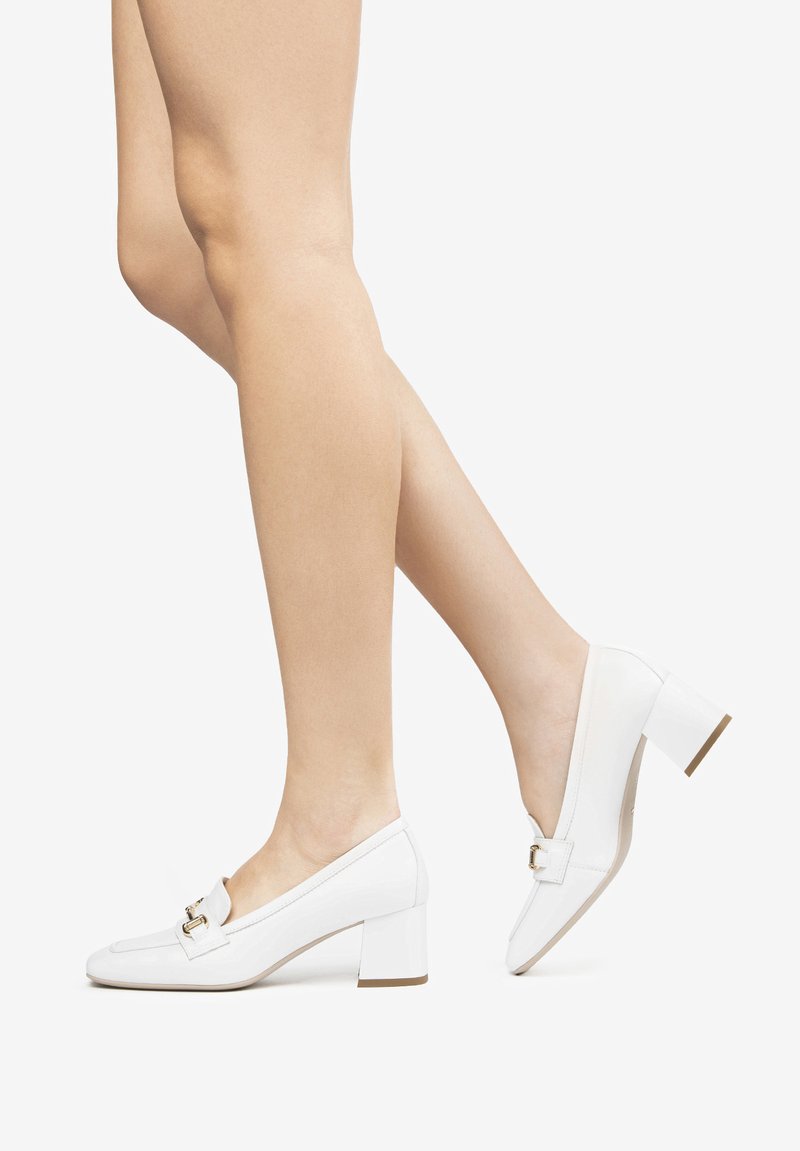 Zapatos de charol blancos con tacón cuadrado y puntera redondeada, que presentan un detalle decorativo de hebilla metálica en la parte superior.