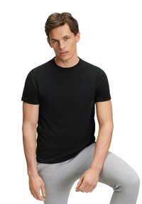 Black cotton T-shirt with short sleeves and a crew neck, paired with gray sweatpants. Smooth texture, plain design, fitted silhouette.