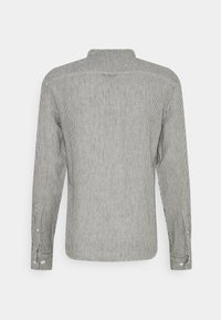 Gestreiftes Langarmhemd in Schwarz und Weiß; verfügt über einen Kragen, Knopfmanschetten und einen geraden Schnitt. Die Rückansicht zeigt ein vertikales Muster.