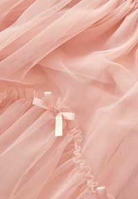 Fabric in tulle rosa chiaro con bordi arricciati e delicati fiocchi in satin. Texture morbida con una qualità trasparente e dettagli arricciati sottili.