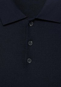 Marineblauwe gebreide poloshirt met drie zwarte knopen en een platte kraag, die de gedetailleerde textuur van de stof en de stiksels toont.